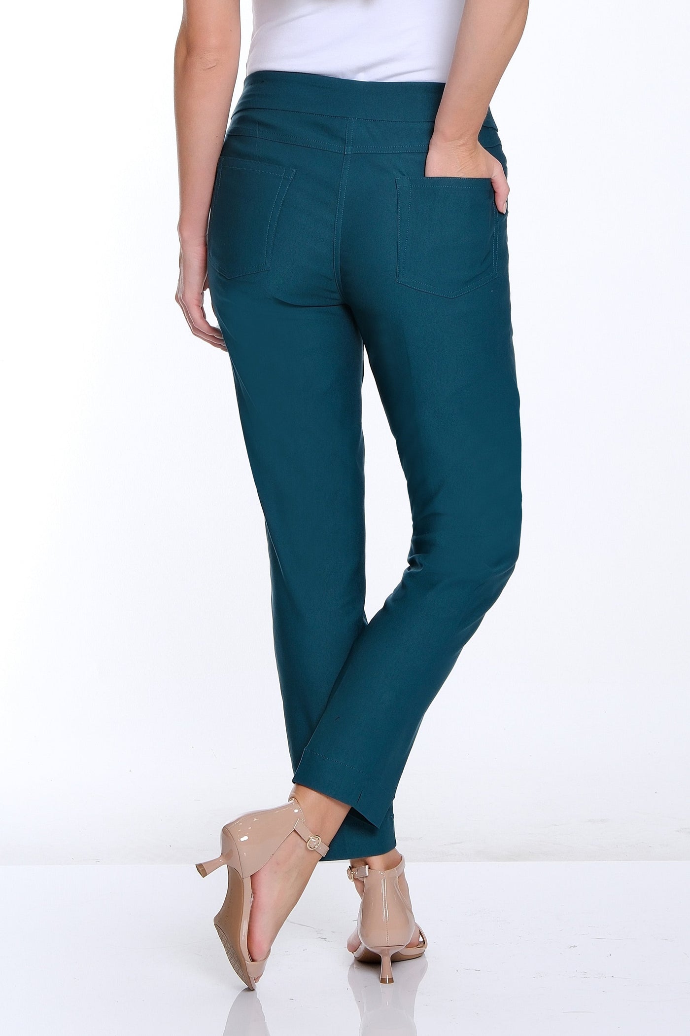 Woman wearing teal pants and a white top on a white background