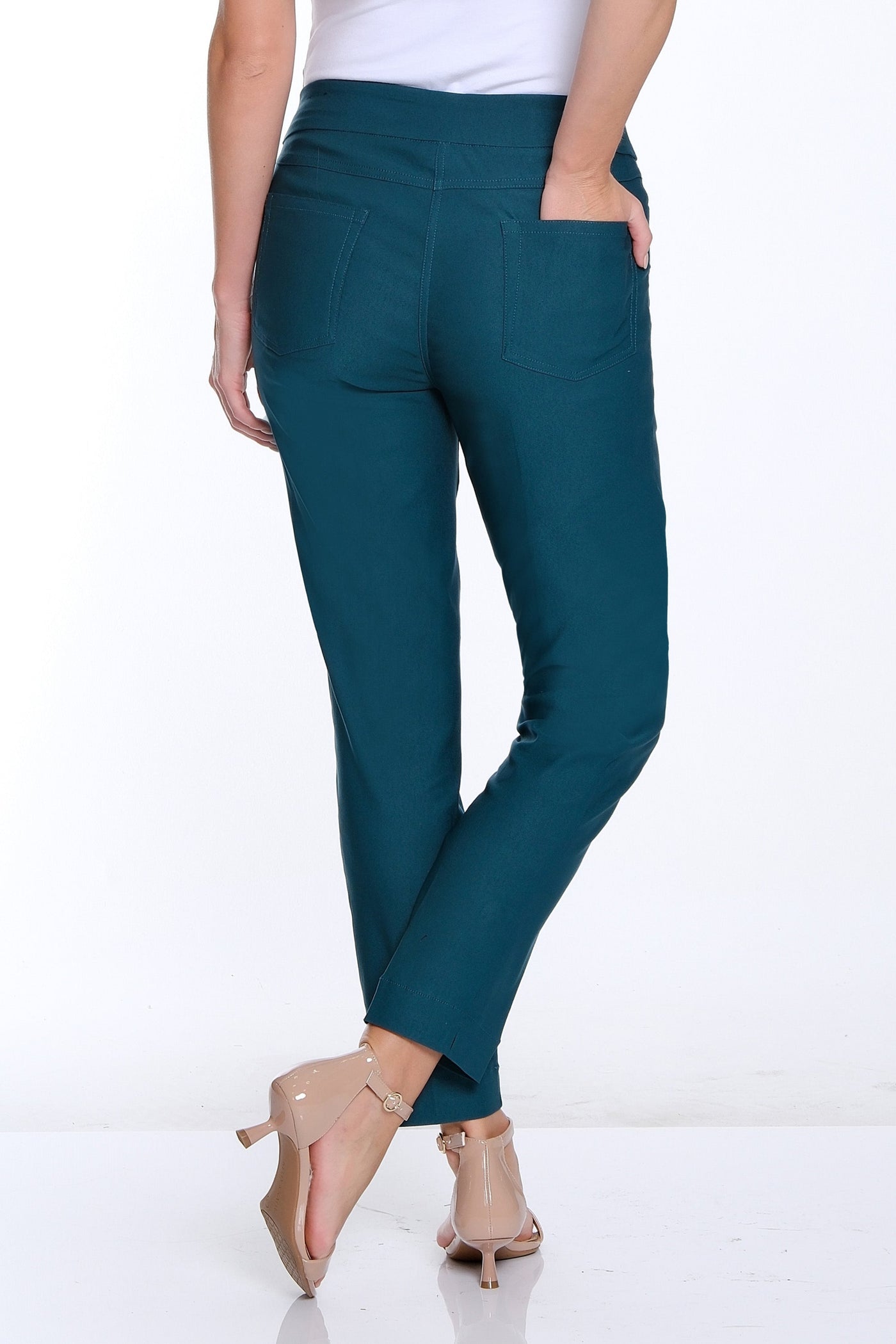 Woman wearing teal pants and a white top on a white background