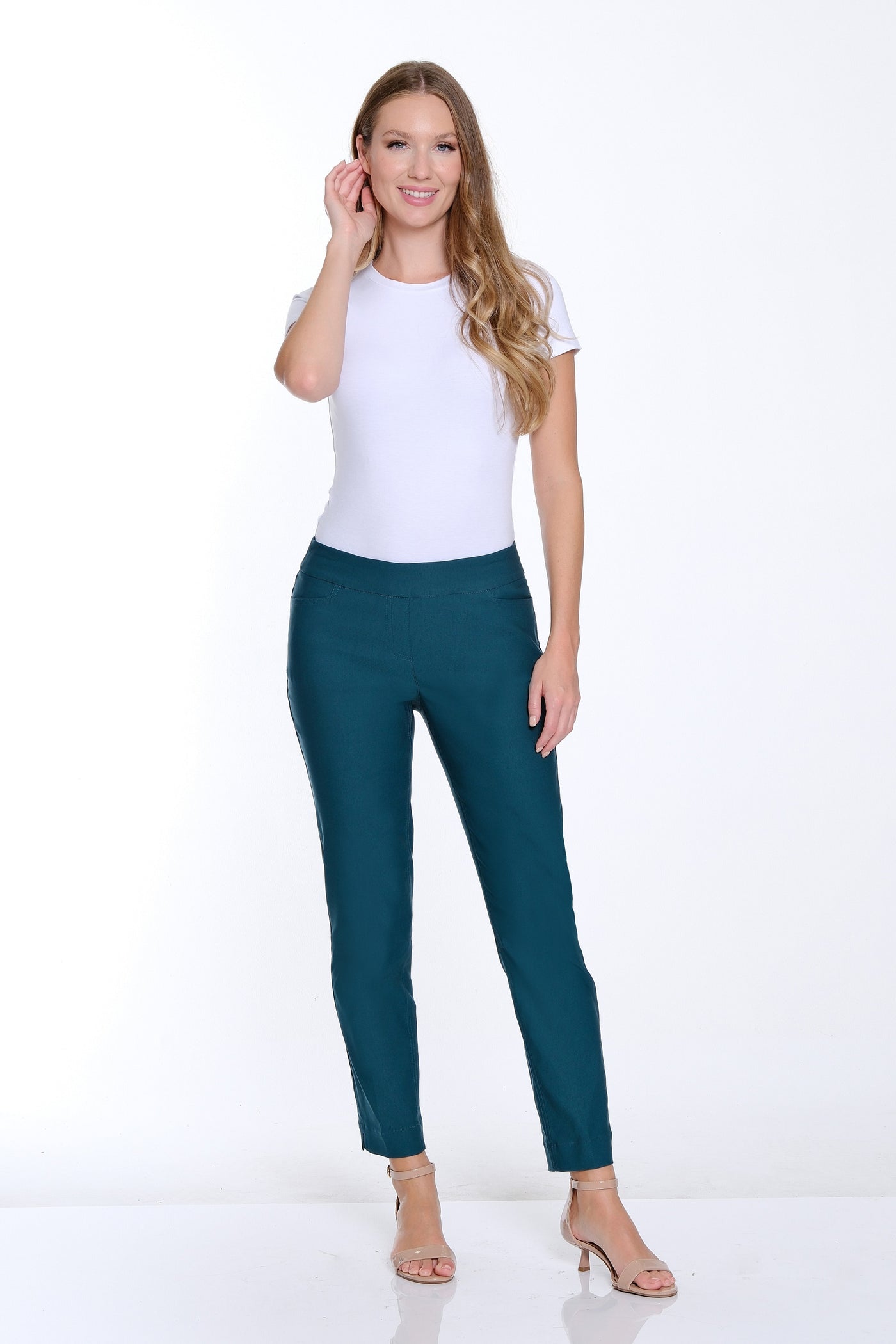 Woman wearing a white top and teal pants on a white background