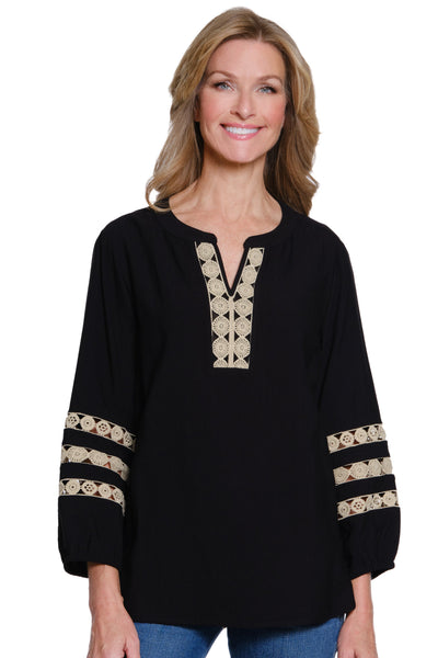 Woman wearing a black top with gold embroidery on a white background