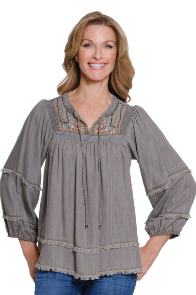 Woman wearing a gray embroidered blouse on a white background
