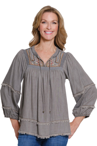 Woman wearing a gray embroidered blouse on a white background