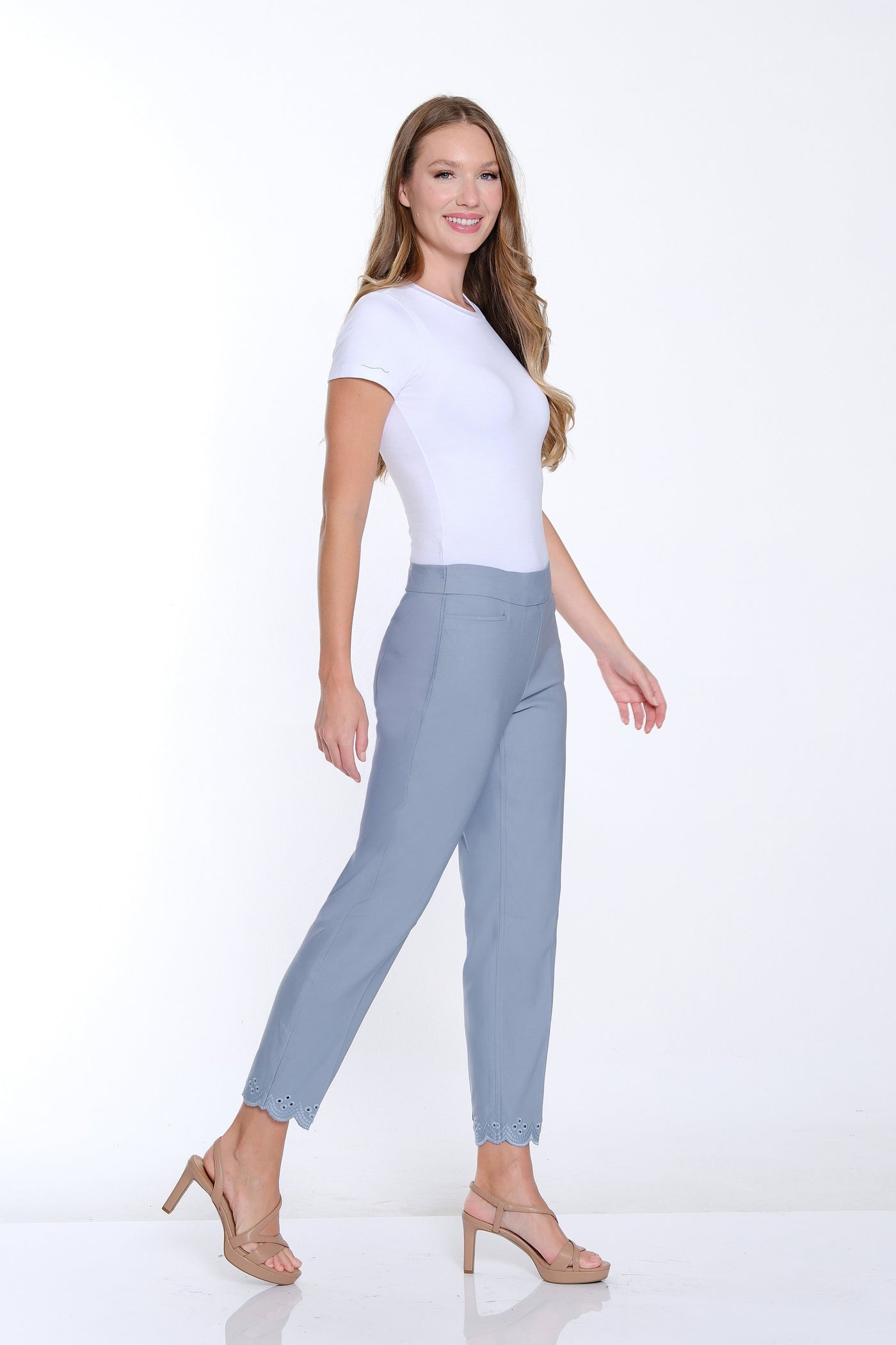 Woman wearing a white top and light gray pants on a white background