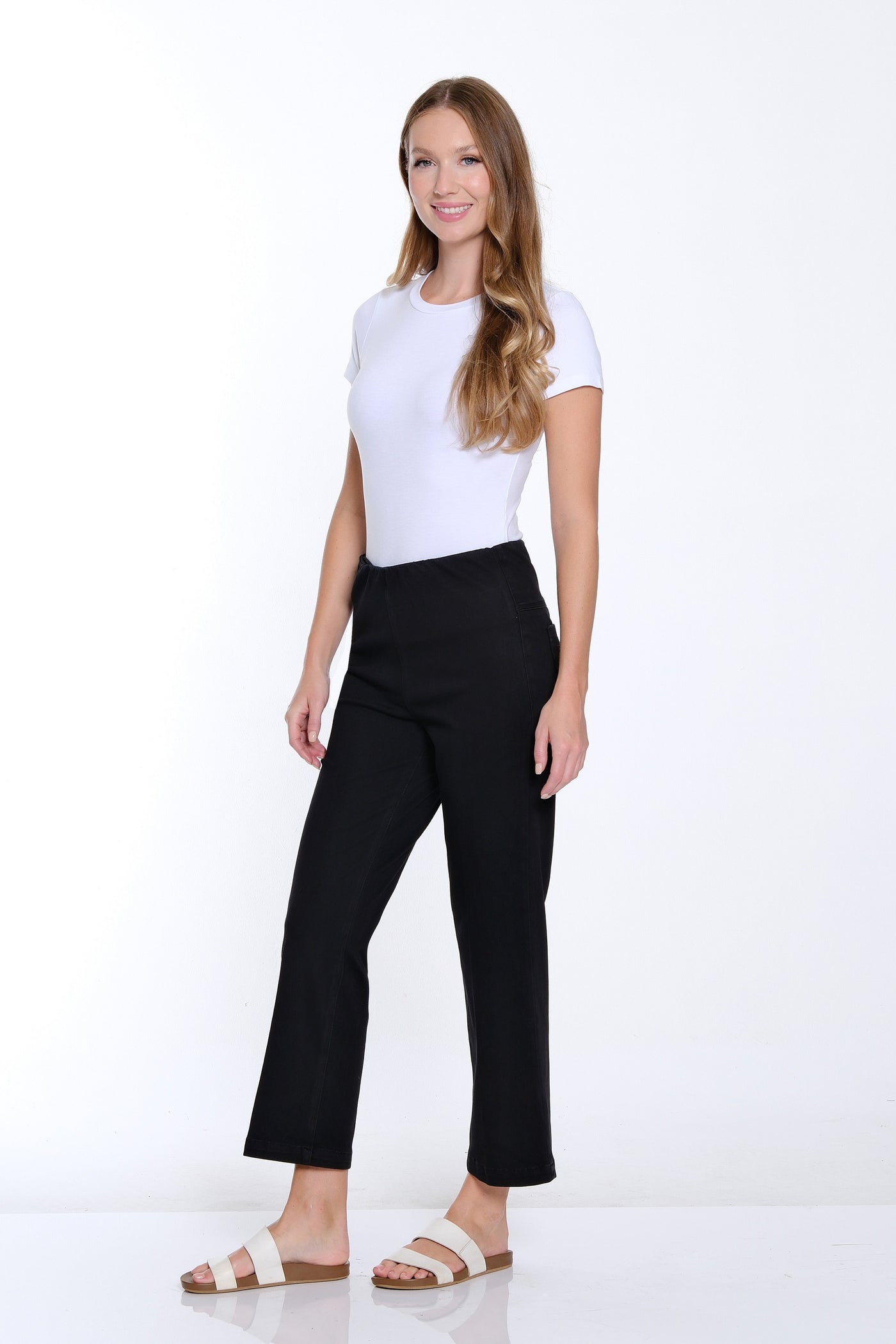 Woman wearing a white top and black pants on a white background