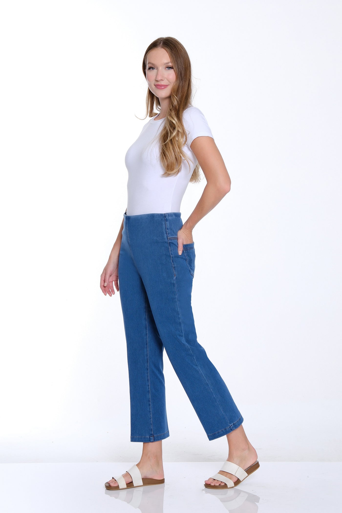 Woman wearing a white top and blue jeans on a white background