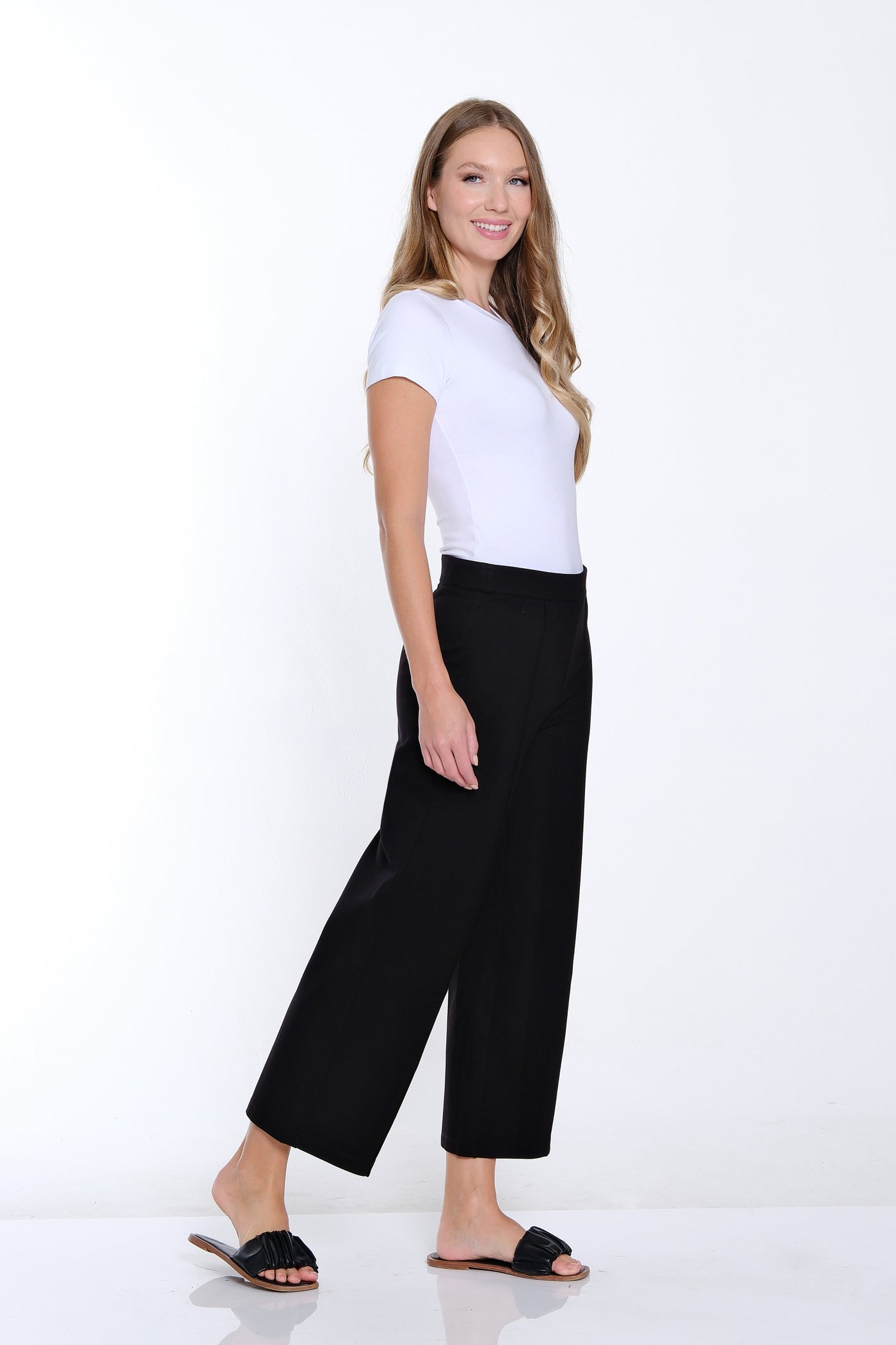 Woman wearing a white t-shirt and black pants on a white background