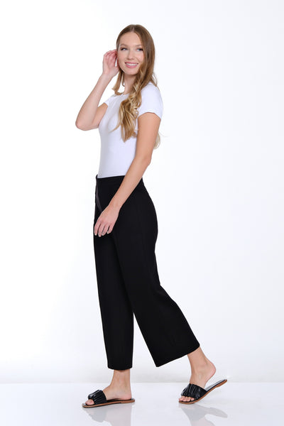 Woman wearing a white top and black pants on a white background