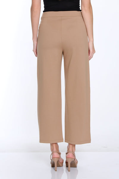 Woman wearing a black top and beige pants on a white background