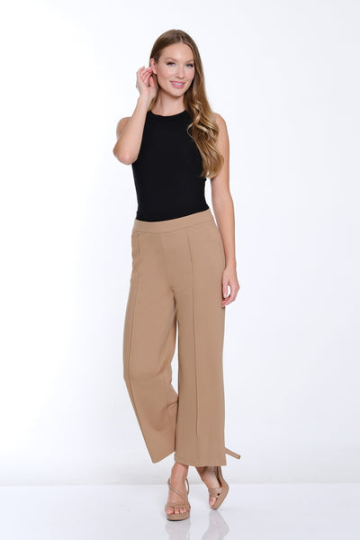 Woman wearing a black top and beige pants on a white background