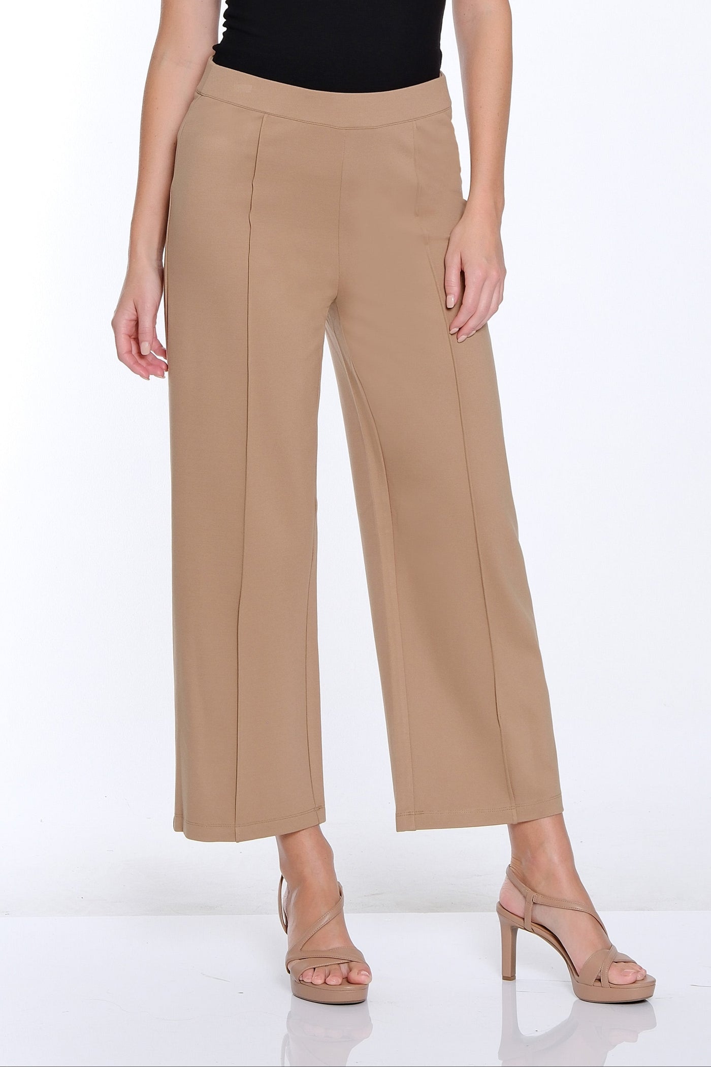 Woman wearing a black sleeveless top and beige wide-leg pants on a white background