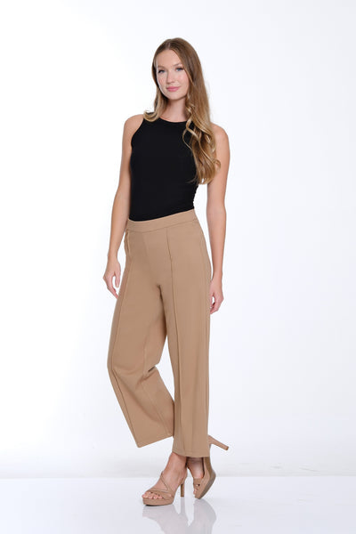 Woman wearing a black top and beige pants on a white background
