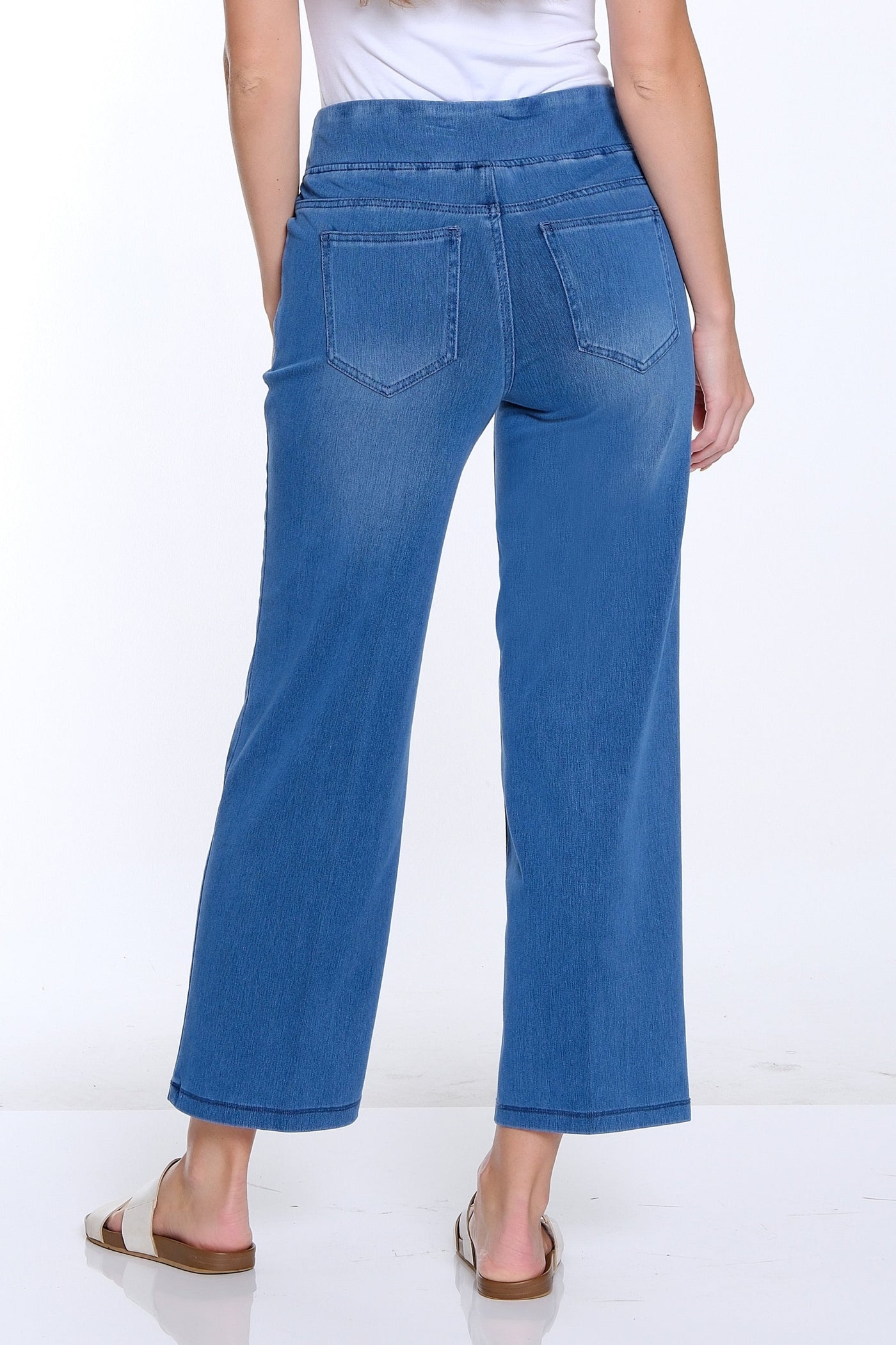 Woman wearing blue jeans and a white top on a white background