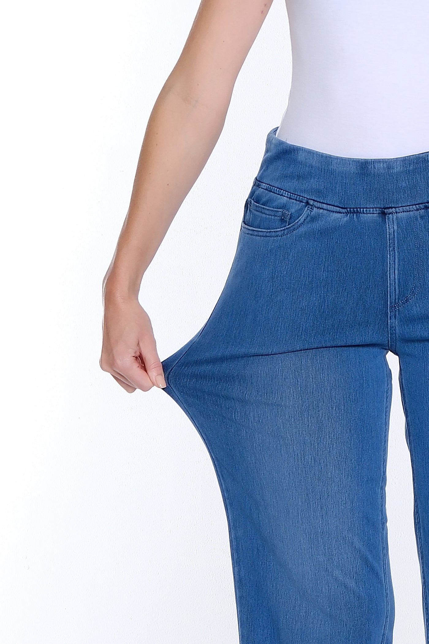 Blue jeans being stretched by a person on a white background