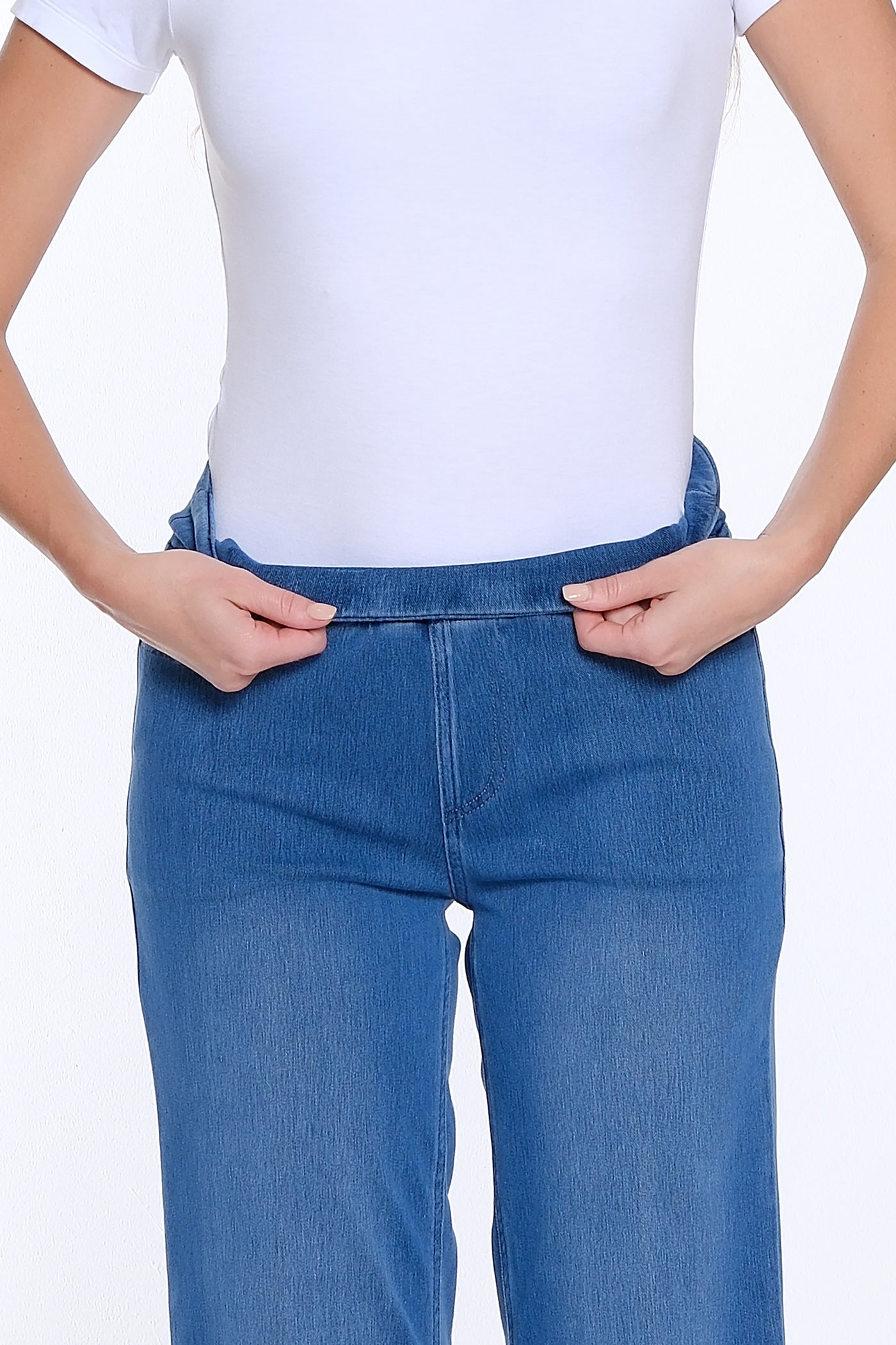 Person wearing blue jeans and a white top on a white background