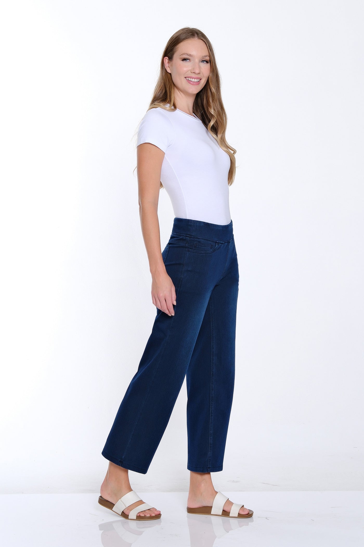 Woman wearing a white top and blue pants on a white background