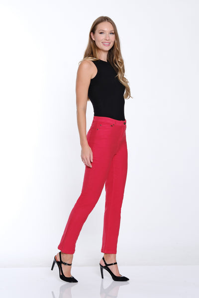 Woman wearing a black sleeveless top and bright pink pants on a white background
