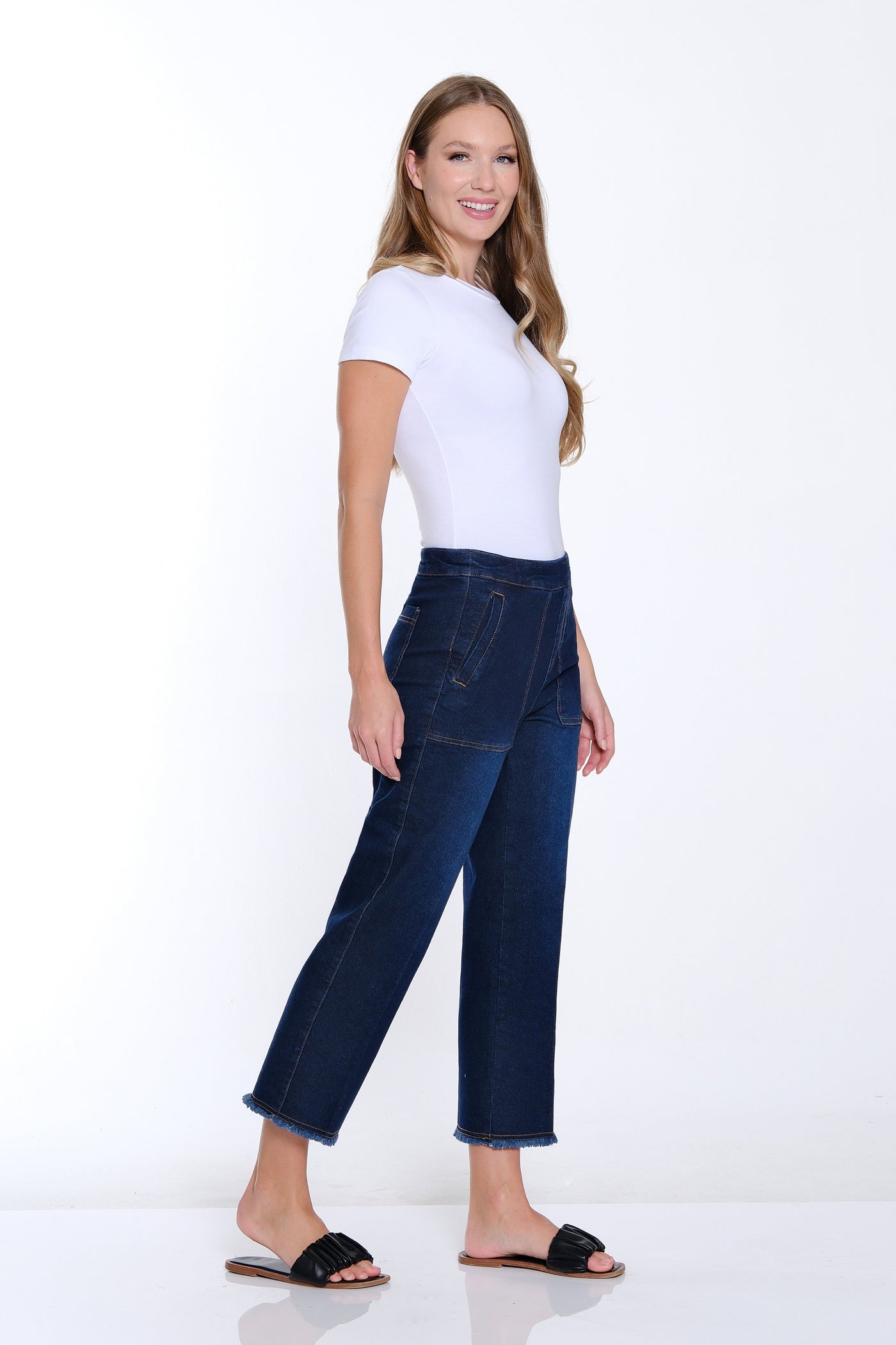 Woman wearing a white top and blue jeans on a white background