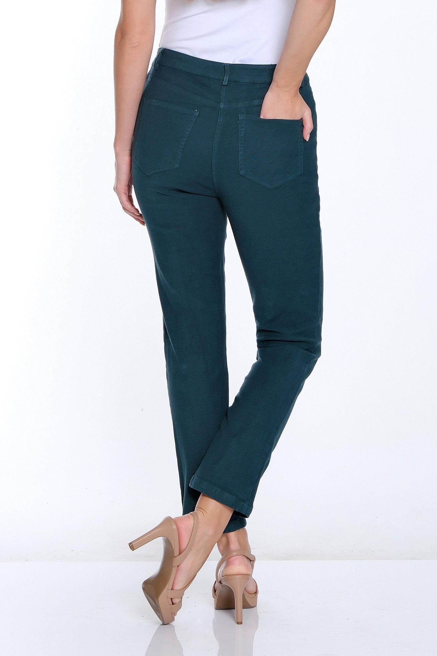 Woman wearing teal pants and a white top on a white background