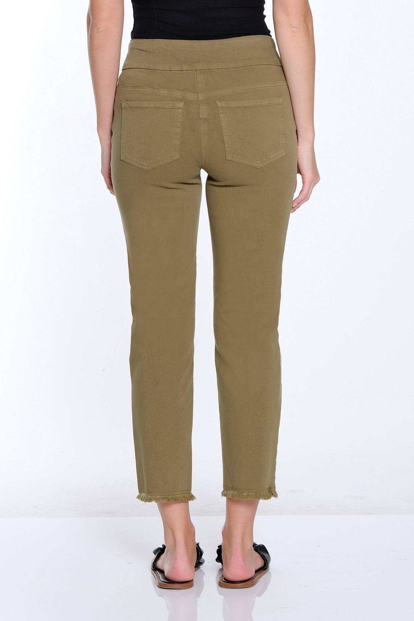 Woman wearing olive green pants and a black top on a white background
