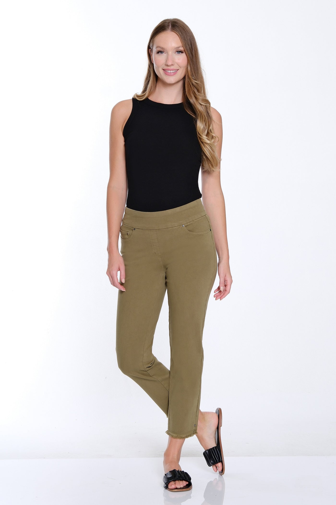 Woman wearing a black top and green pants on a white background