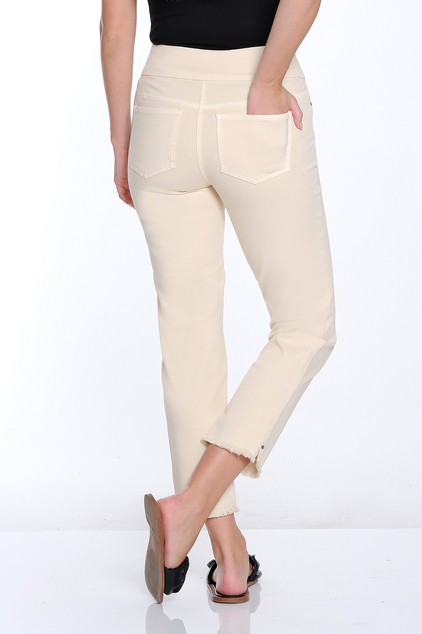 Woman wearing a black top and cream pants on a white background
