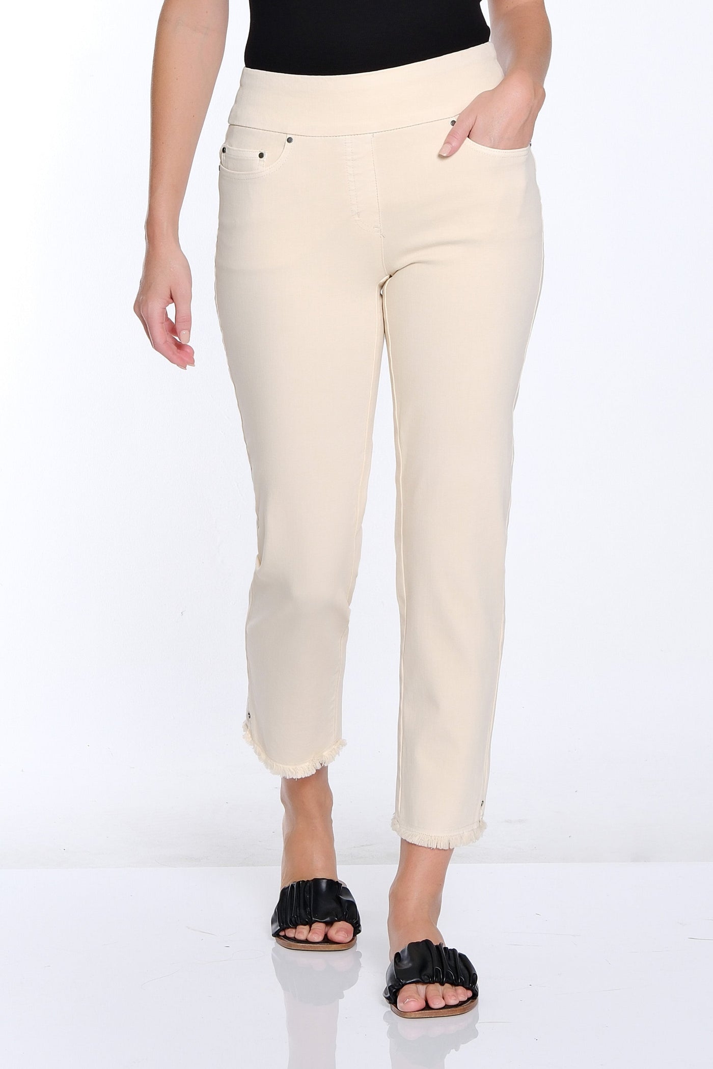 Woman wearing a black sleeveless top and beige pants on a white background