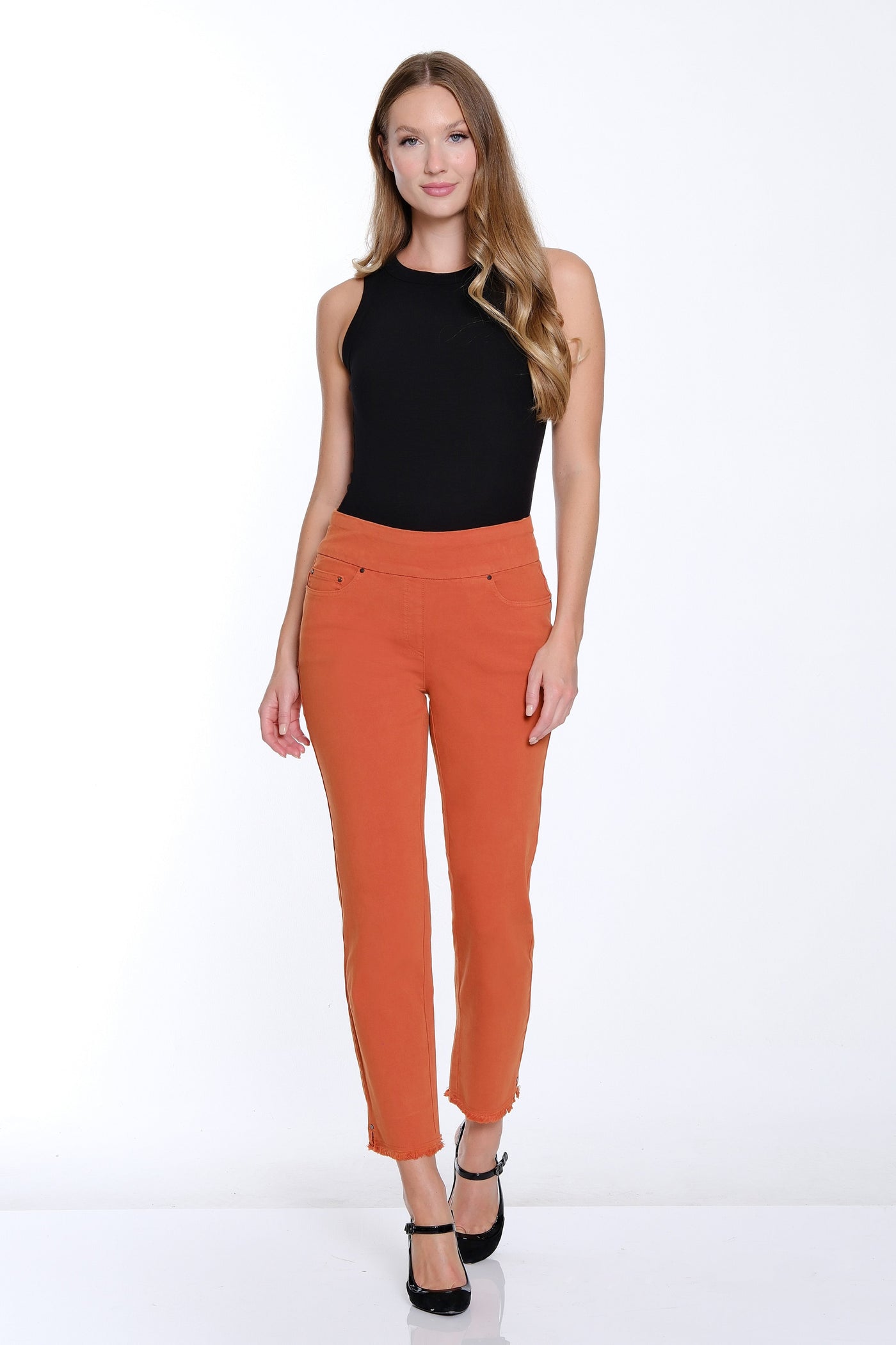 Woman wearing a black top and orange pants on a white background