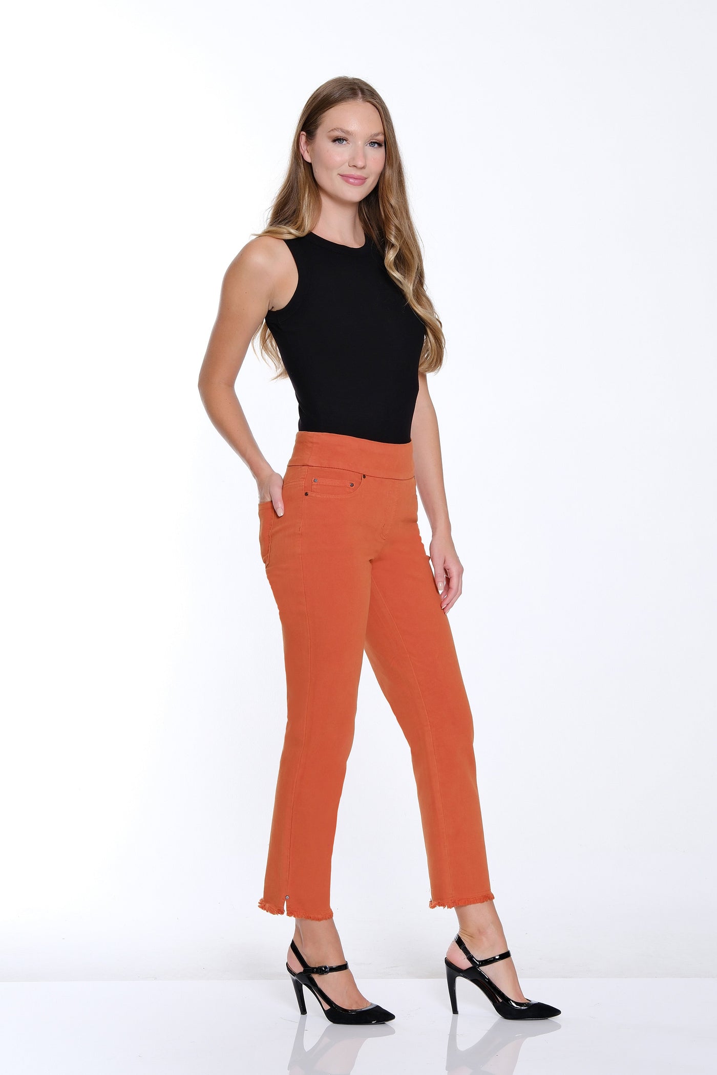 Woman wearing orange pants and a black top on a white background