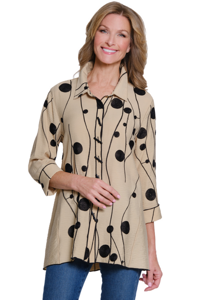 Woman wearing a beige blouse with black polka dot pattern on a white background